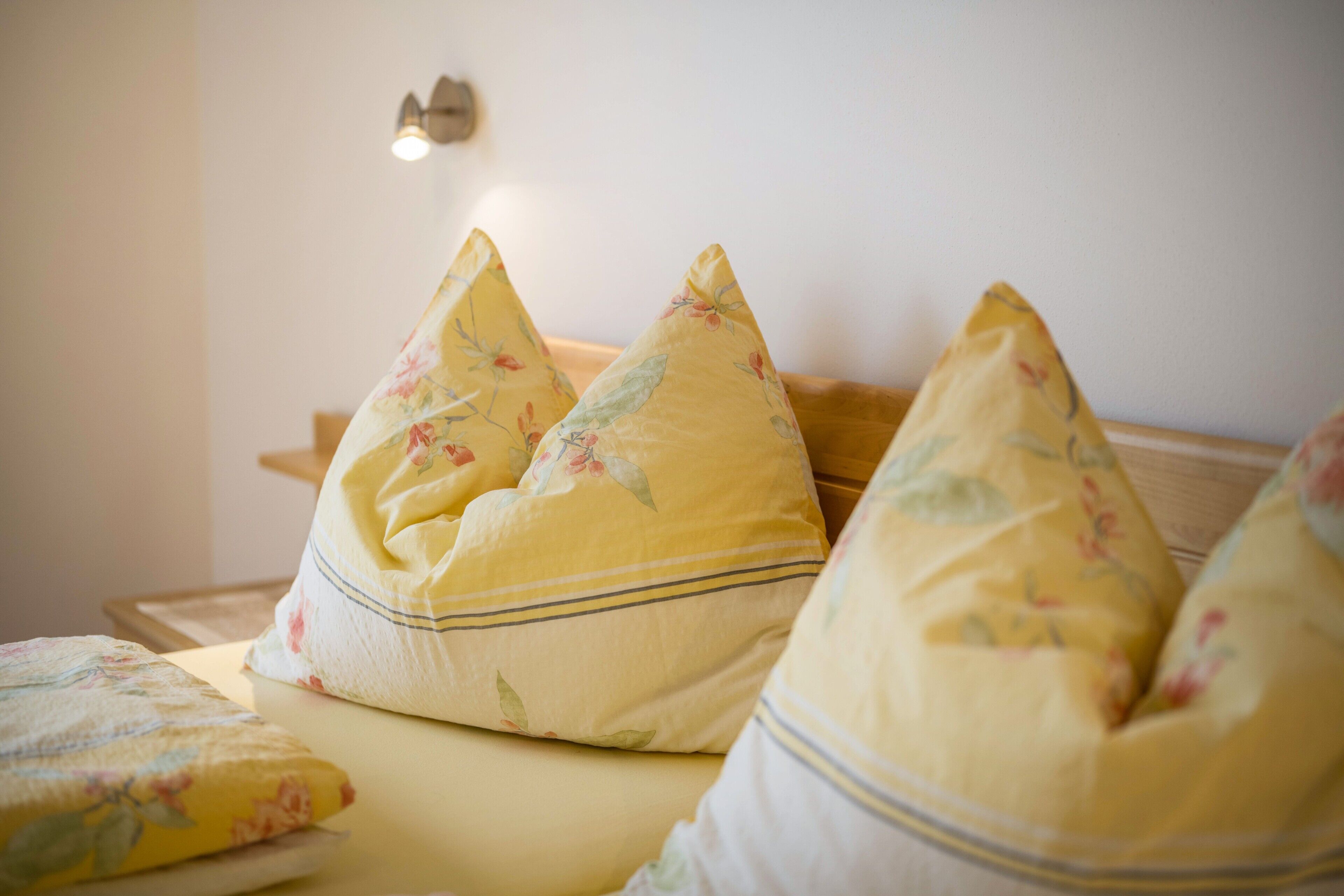 A bed with floral-patterned pillows and a matching blanket.
