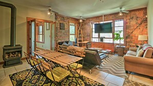 A cozy living room with a fireplace, wooden furniture, and a brick wall. - Hip Midtown Detroit Hub, Walk to Woodward Ave (Detroit)