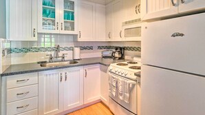Une cuisine avec des meubles blancs, une cuisinière, un four à micro-ondes et un réfrigérateur.