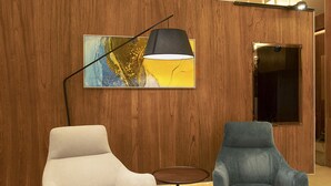 Deux fauteuils, une lampe et un tableau dans un hall d’entrée moderne, avec des lambris en bois et un sol carrelé.