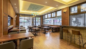 L’intérieur d’un restaurant est agrémenté de lambris en bois, de grandes fenêtres et propose différents types de sièges, notamment des tables et des tabourets de bar.