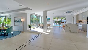 Un vaste espace de vie moderne comprenant une table à manger, des chaises et une grande fenêtre donnant sur une piscine.