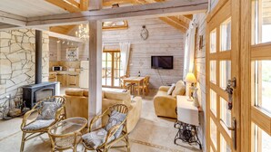 Ein gemütliches Blockhaus-Interieur mit Kamin aus Stein, Korbmöbeln und einem Fernseher.
