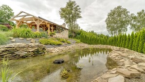 Ein hölzerner Pavillon mit Steinmauern, einem Teich und umgebender Bepflanzung.