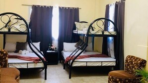 A room with two bunk beds, a small table, and two chairs.