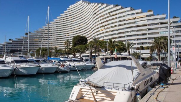 A marina with yachts docked in front of a modern hotel with a curved facade. - La Calmeraie by Interhome (Villeneuve-Loubet)