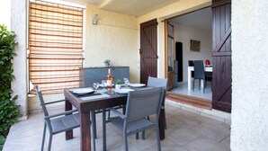 A dining area with a table set for four, a sofa, and a TV in the background. - La Calmeraie by Interhome (Villeneuve-Loubet)