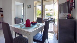 A dining area with a table set for two, a red kettle, and a bowl of fruit. - La Calmeraie by Interhome (Villeneuve-Loubet)
