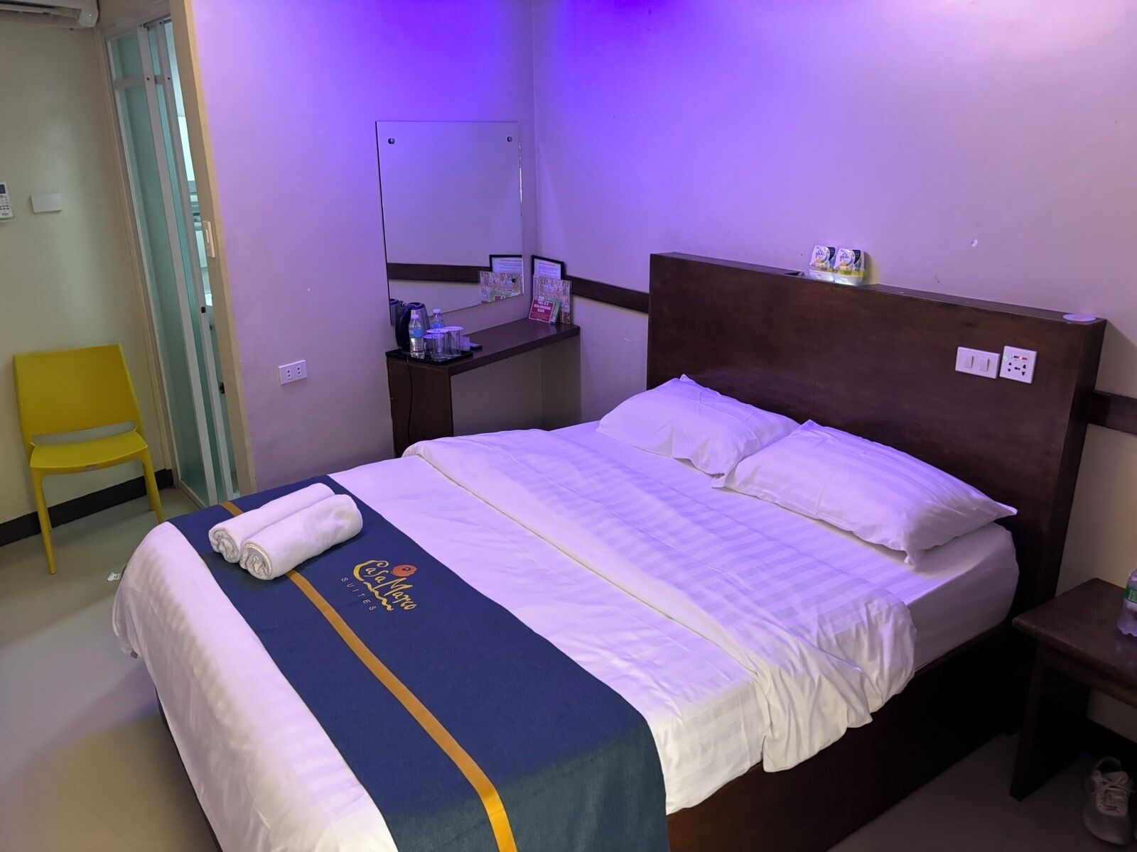 Une chambre d’hôtel avec un lit, une chaise, un bureau et un miroir.