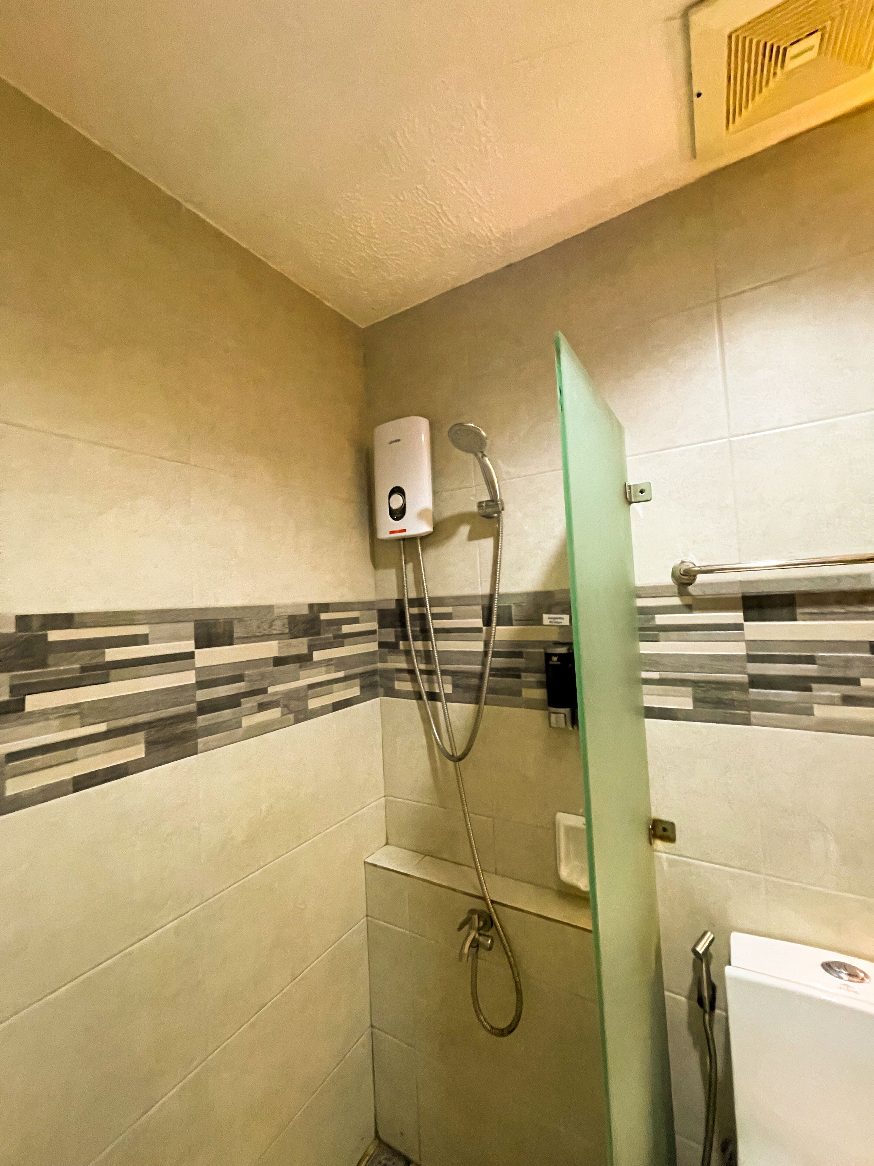 A bathroom with a shower, a hand dryer, and a toilet.