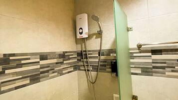 A bathroom with a shower, a hand dryer, and a toilet.