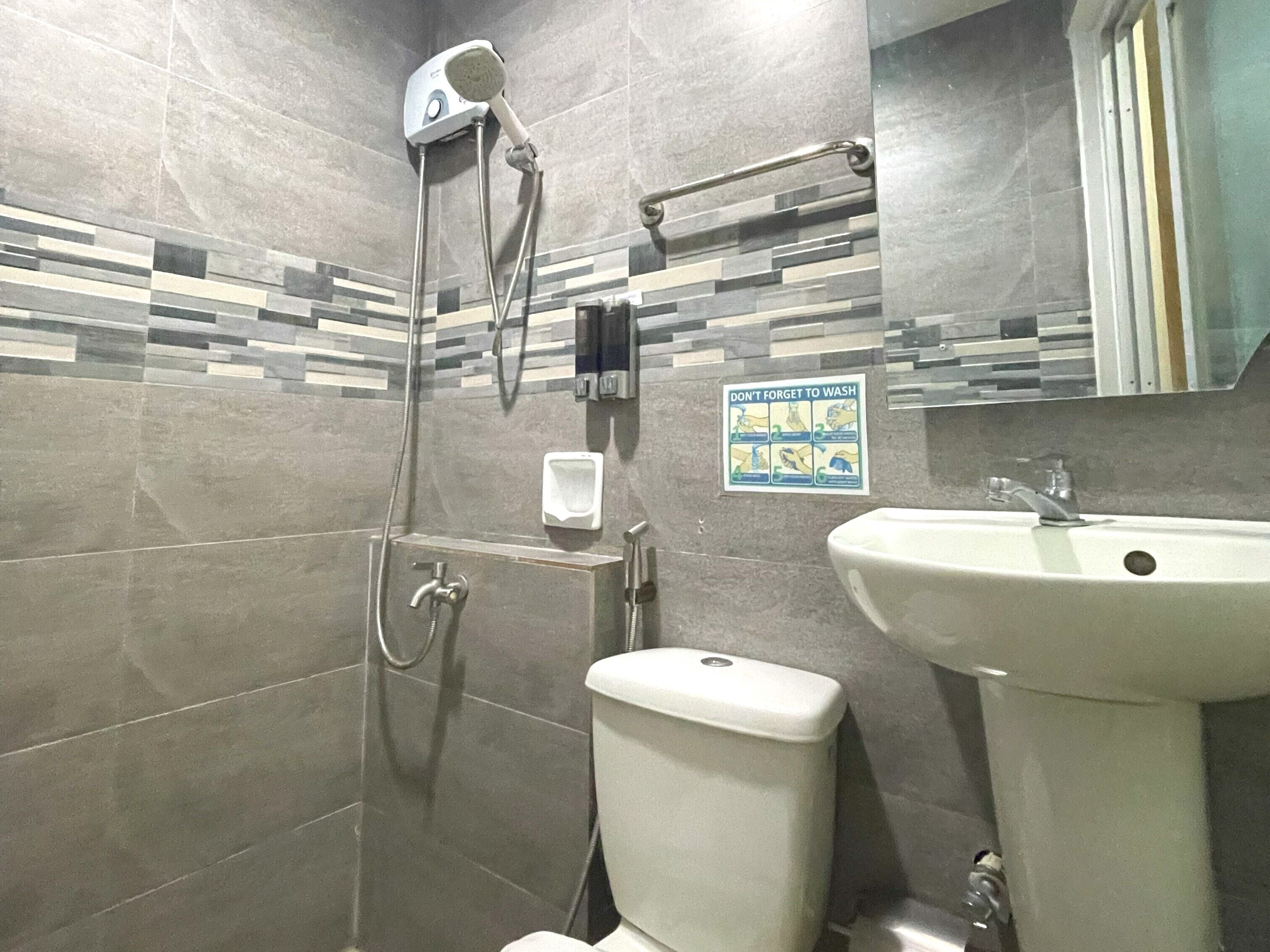 A bathroom with a shower, toilet, sink, and a hand dryer.