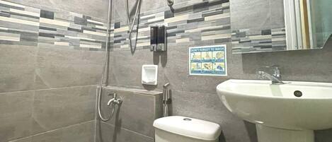A bathroom with a shower, toilet, sink, and a hand dryer.