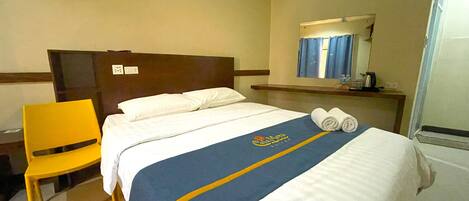 Una habitación de hotel con una cama, una silla, una mesita de noche y un espejo.