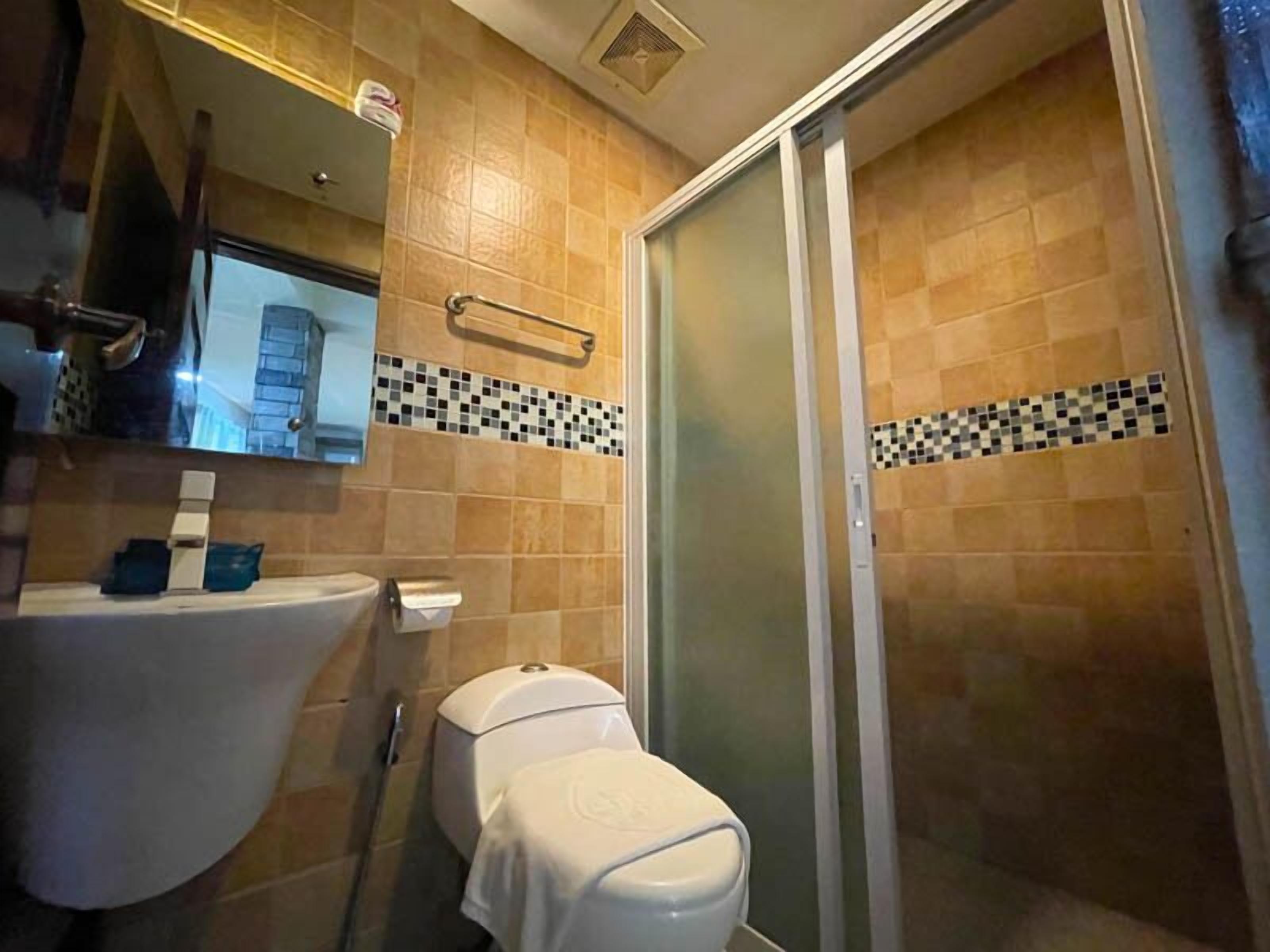 A bathroom with a toilet, sink, and a shower area.