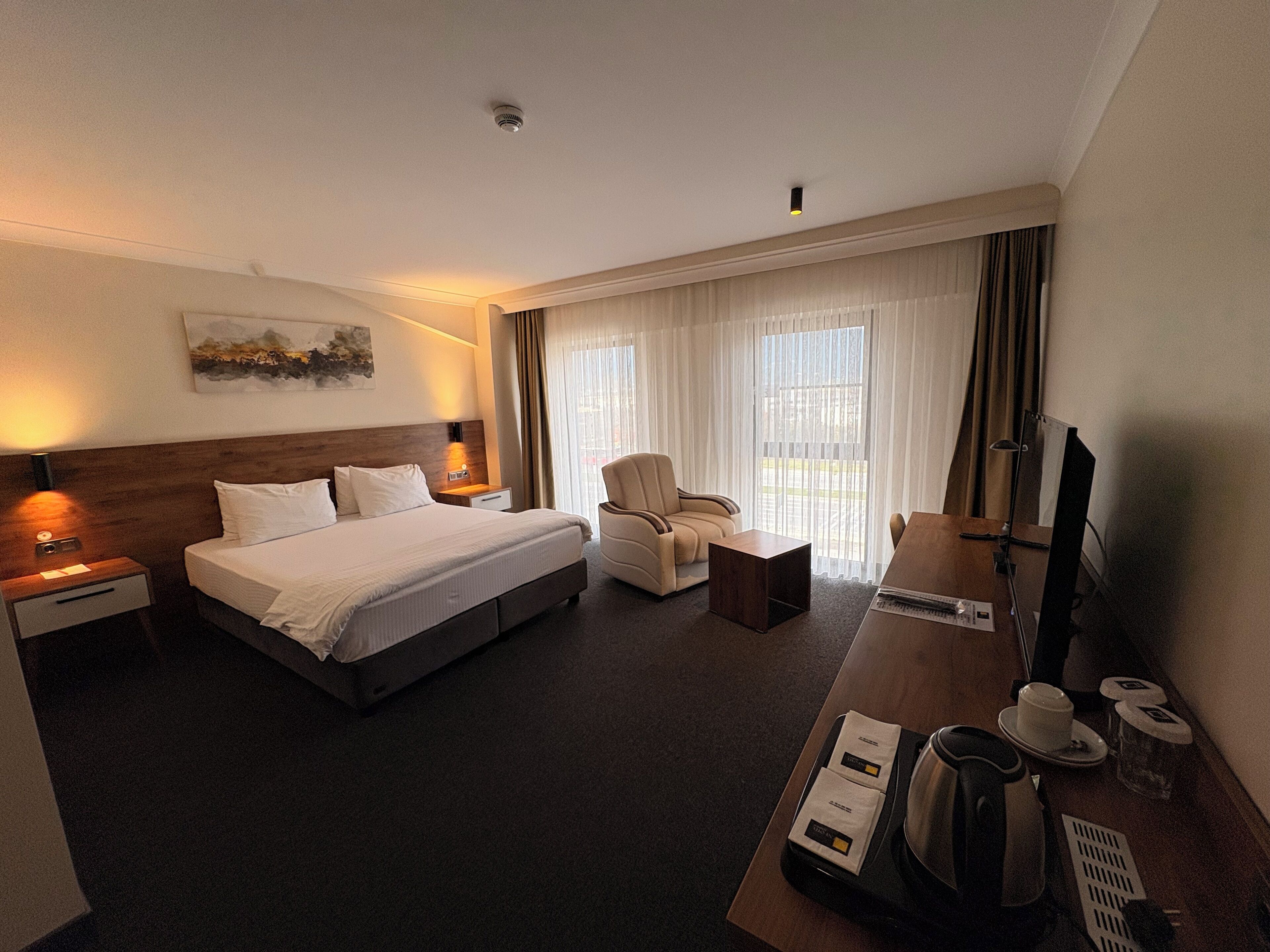Habitación de hotel con una cama grande, un escritorio con computadora, una silla y un televisor.