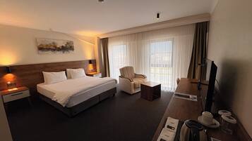 Habitación de hotel con una cama grande, un escritorio con computadora, una silla y un televisor.