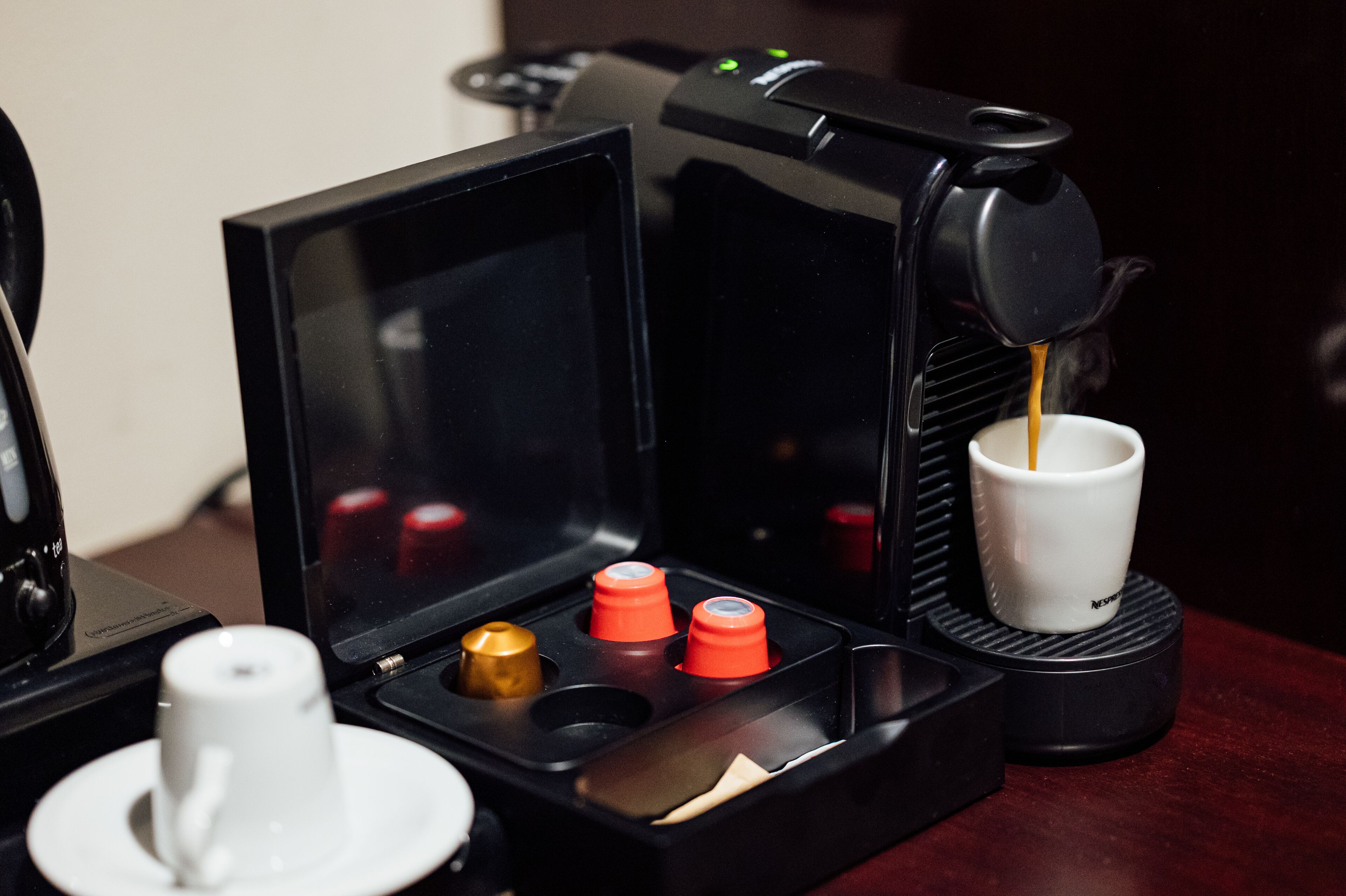 Uma máquina de café com um porta-xícaras e uma xícara sobre uma mesa.