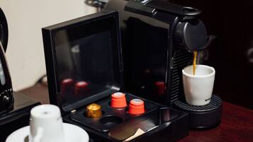 Uma máquina de café com um porta-xícaras e uma xícara sobre uma mesa.