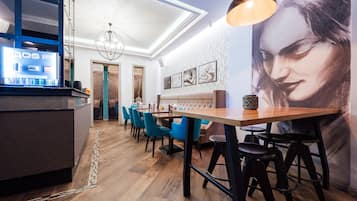 Interior moderno de restaurante com área de bar, piso de madeira, cadeiras azuis e um grande mural na parede.