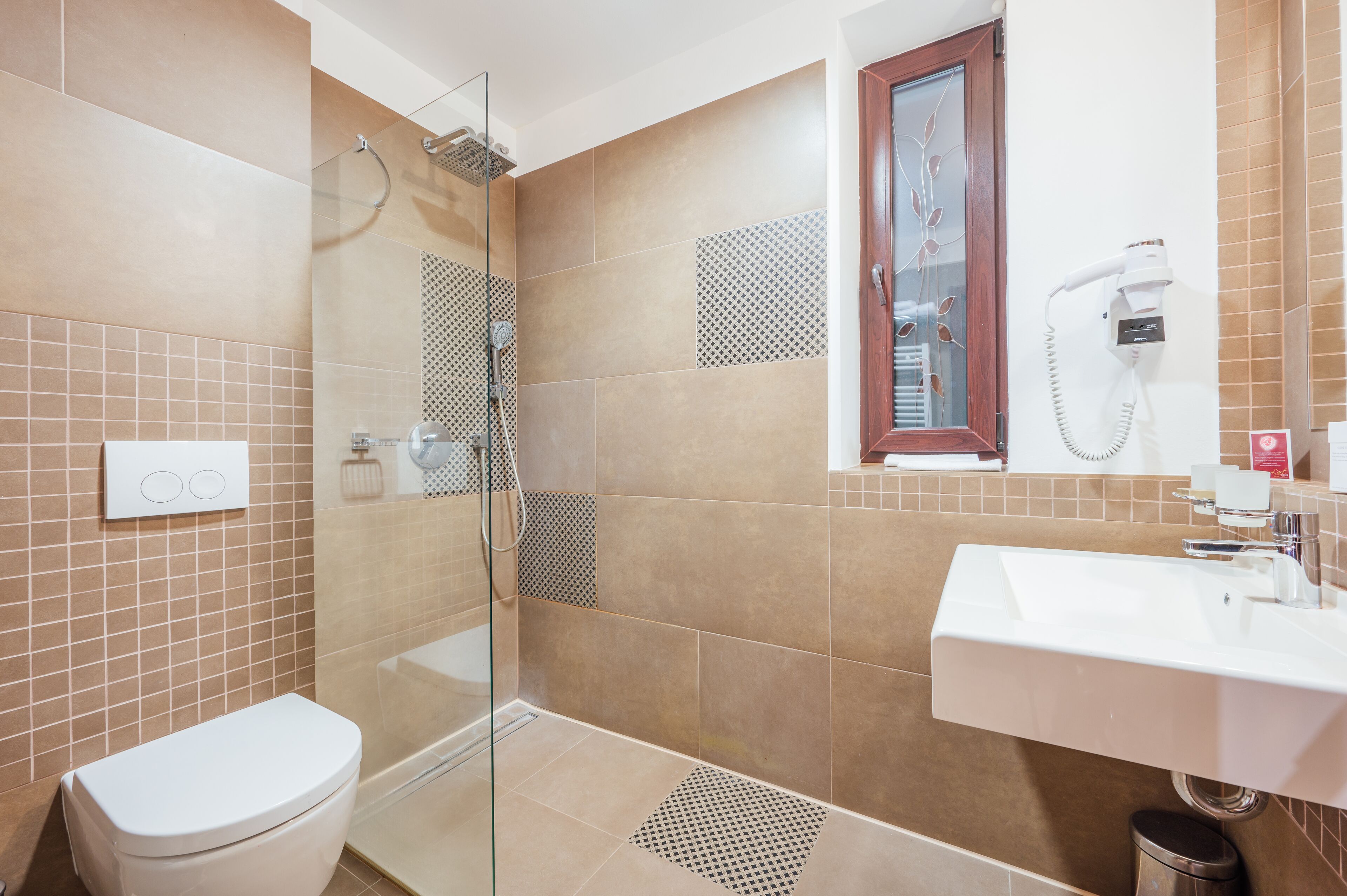 Un baño moderno con cabina de ducha de vidrio, un lavabo blanco y un inodoro.