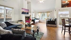 A spacious living area with a fireplace, a flat-screen TV, and a dining table.