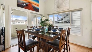 A dining area with a wooden table set for six, surrounded by chairs.