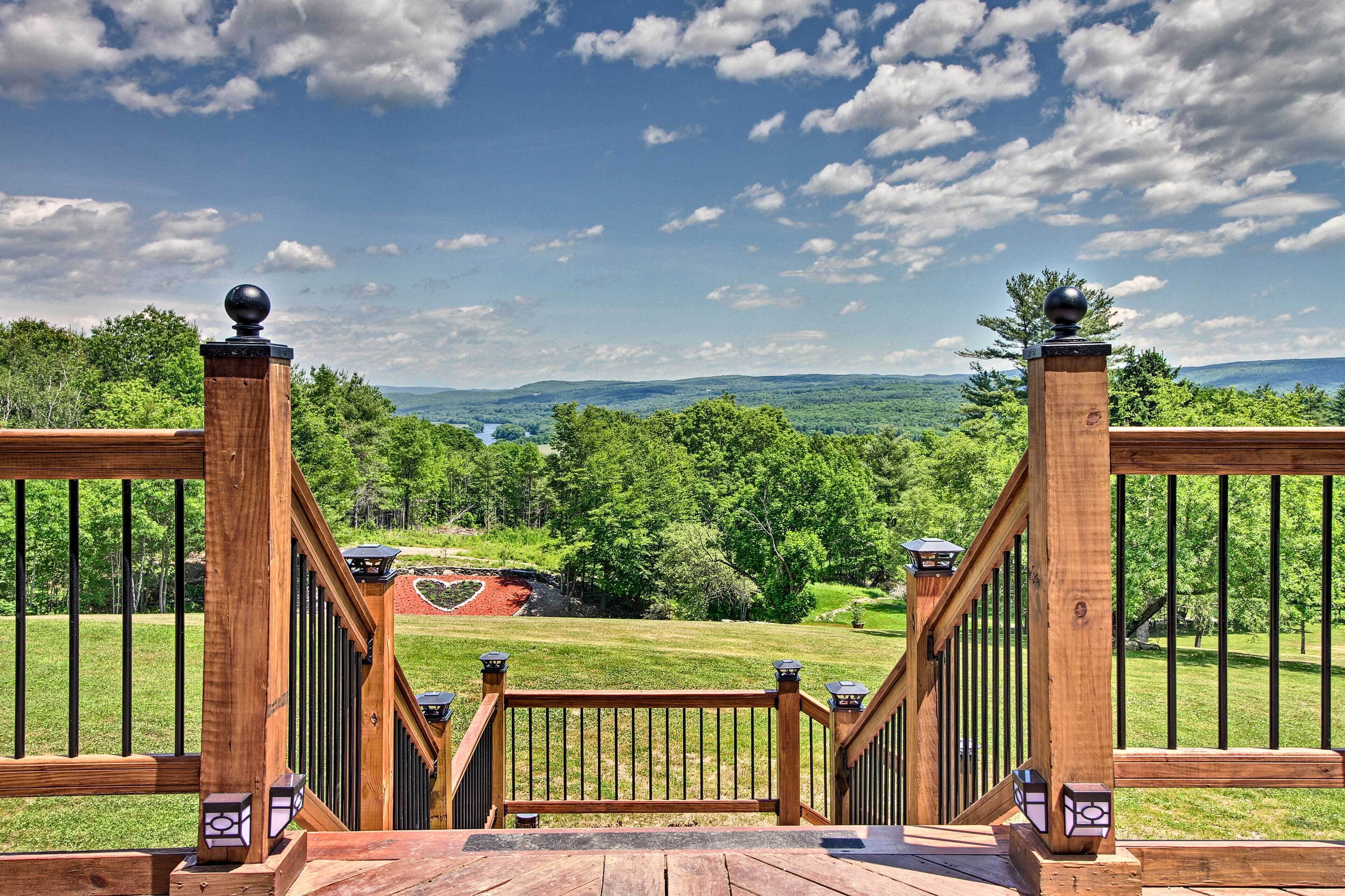 Una terraza de madera con vista a un paisaje verde y montañas distantes.