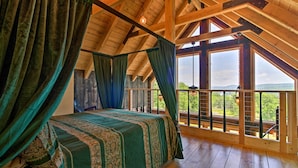 Una habitación con techo de madera, una cama grande con ropa de cama verde y un balcón con vistas al exterior.