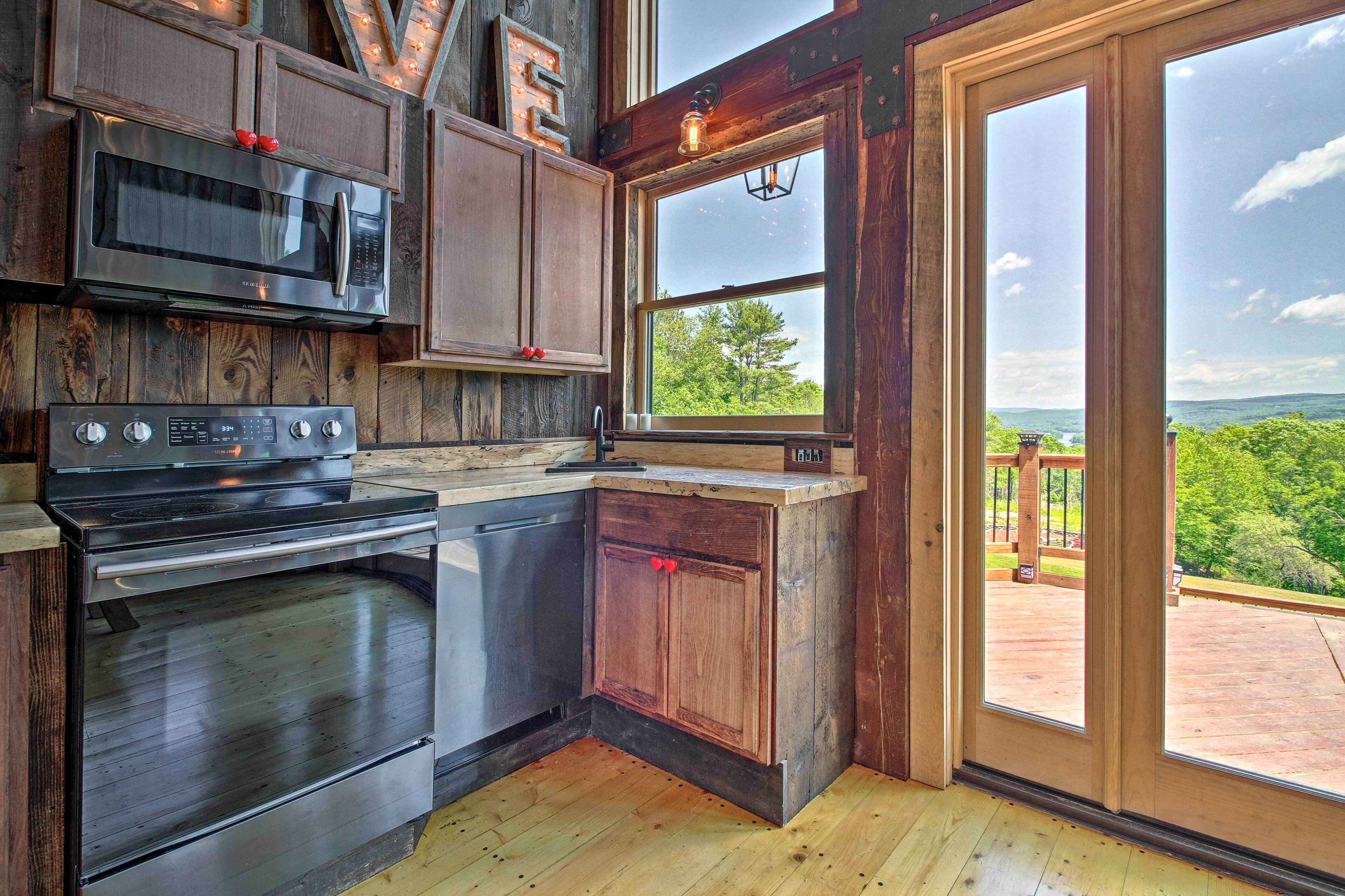 A kitchen with a large window, a microwave, an oven, and wooden cabinets.
