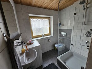 A bathroom with a sink, a window, a shower, and a toilet. - Vacation apartment Alpenvorland am Lech (Apfeldorf)