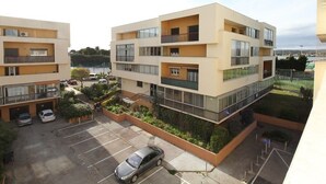 Un immeuble résidentiel à plusieurs étages, doté de balcons, d’un espace de stationnement et offrant une vue sur un plan d’eau.