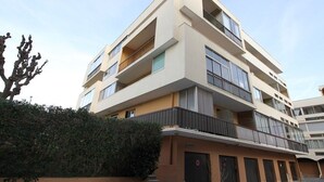 Un immeuble à plusieurs étages, doté de balcons, d’un toit plat et d’une façade beige.
