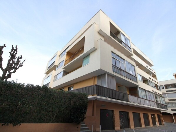 Un edificio de varios pisos con balcones, techo plano y fachada color beige.
