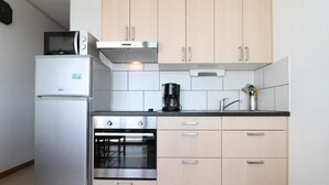 A compact kitchen with a refrigerator, oven, microwave, and a coffee maker on the countertop. - Studio in Balaruc-les-Bains with AC and Wifi (Balaruc-les-Bains)