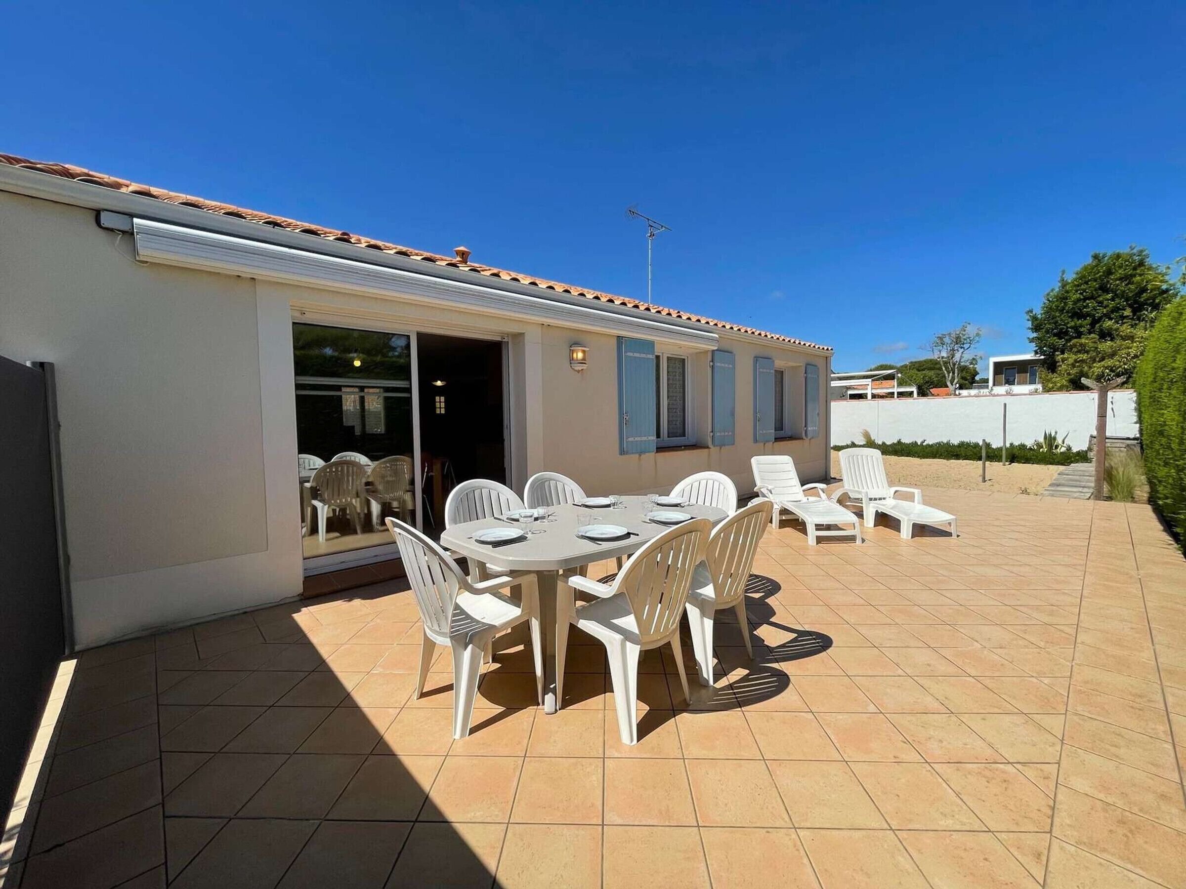 A patio with a table and chairs, a sliding glass door, and a tiled floor.