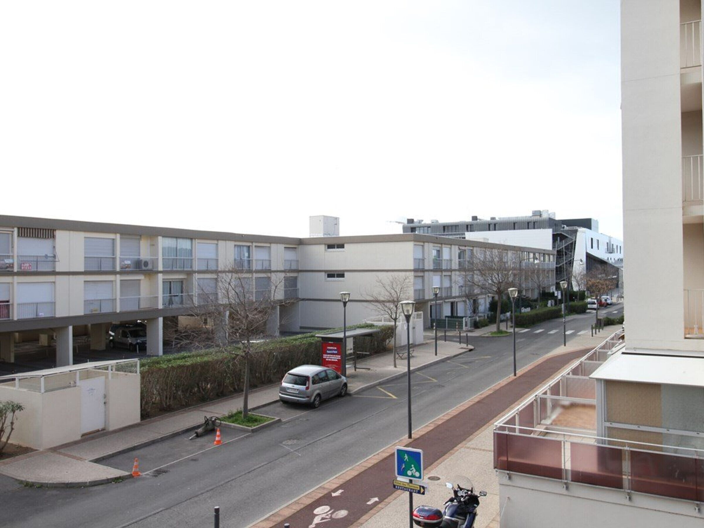 A multi-story building with a parking garage, a street with a bike lane, and a pedestrian pathway.