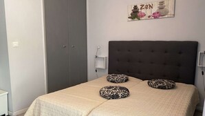Ein Schlafzimmer mit Bett, Kissen, Kopfteil, Kleiderschrank und einem an der Wand hängenden Kunstwerk.