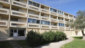 Ein mehrstöckiges Gebäude mit einheitlicher Fassade und Balkonen in jeder Etage, vor strahlend blauem Himmel.