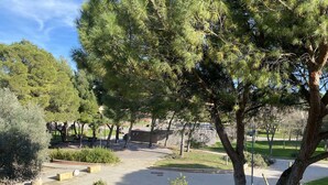 Ein Park mit Bäumen, Bänken und einem gepflasterten Weg.