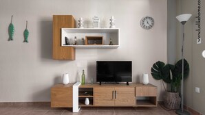 Un soggiorno moderno con un mobile TV in legno, un televisore a schermo piatto e un'ampia pianta in vaso.