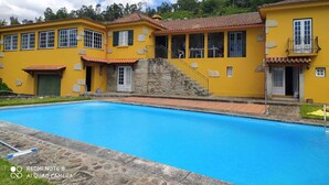 A yellow building with a swimming pool, stone steps, and a balcony.
