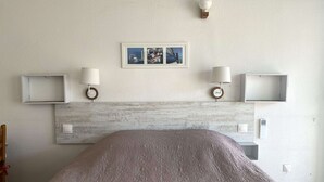Ein Hotelzimmer mit einem Bett, zwei Nachttischlampen, einem Wandbild und einem Lichtschalter.