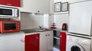 Eine kleine Küche mit Mikrowelle, Toaster, Spüle und Waschmaschine.