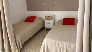 A twin room with two beds, a bedside table with drawers, a mirror, and a window with curtains. - Lovely 1-bedroom apartment with open view, loggia, elevator and wifi in Balaruc-les-Bains (Balaruc-les-Bains)