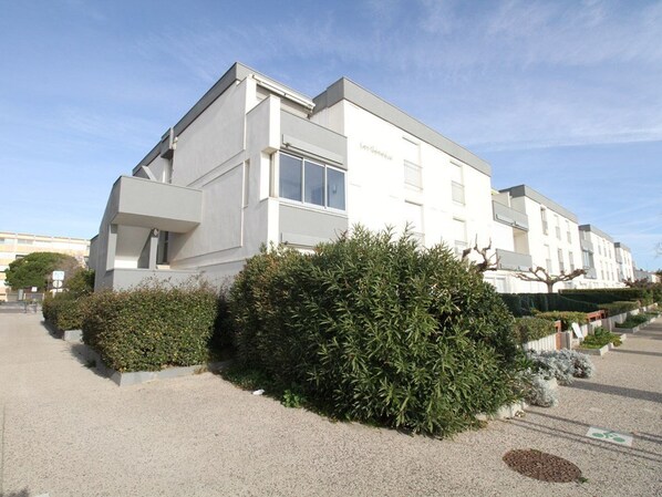 A modern building with a flat roof and large windows, surrounded by well-maintained hedges.