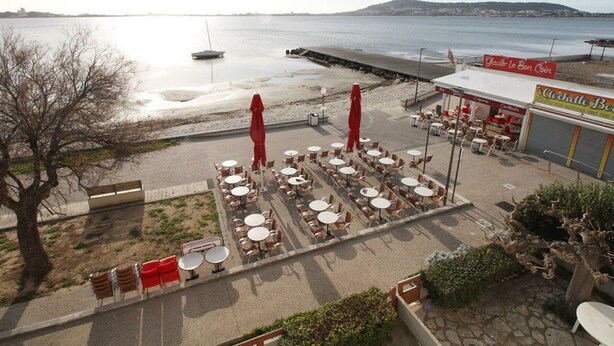 A seaside restaurant with outdoor seating, a view of the water, and a pier in the background. - Air-conditioned studio with WIFI in Balaruc-les-Bains (Balaruc-les-Bains)
