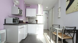 A compact kitchen with white cabinets, a microwave, and a small dining area with a table and chairs. - Air-conditioned studio with WIFI in Balaruc-les-Bains (Balaruc-les-Bains)