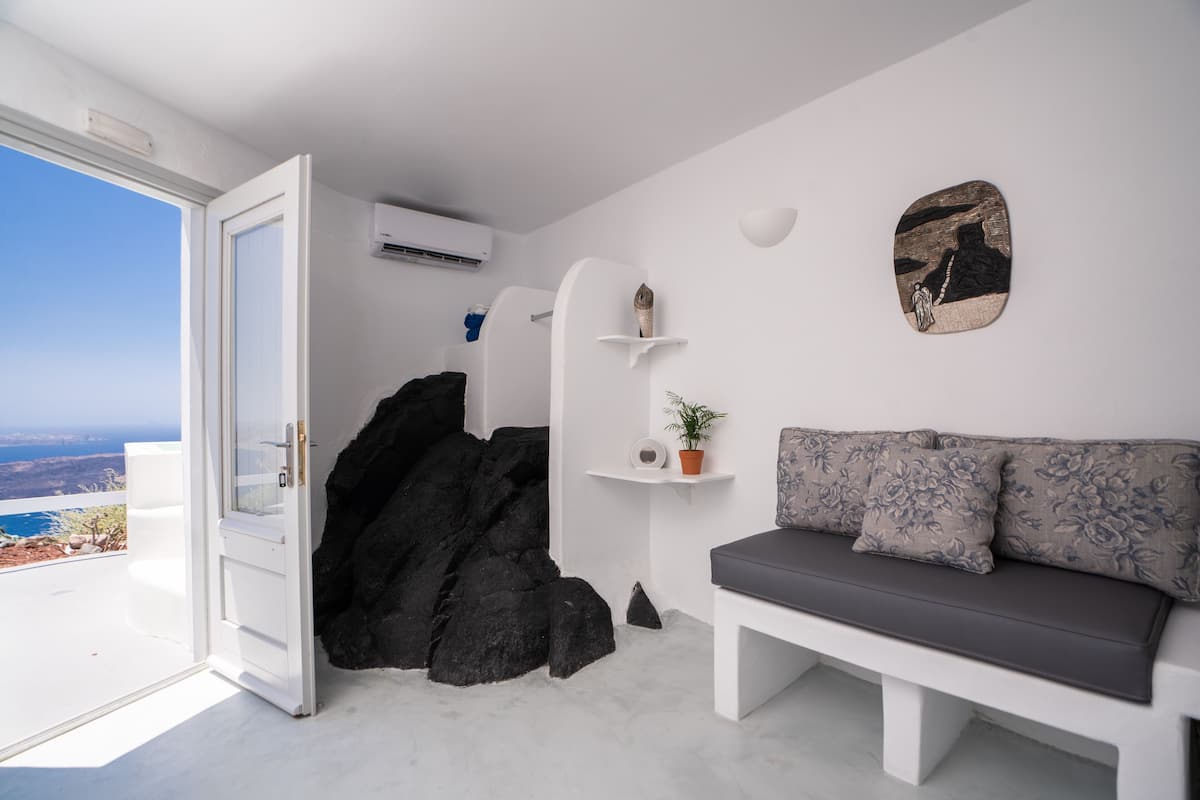 A modern room with a white bench, a rock feature, and a view of the sea.
