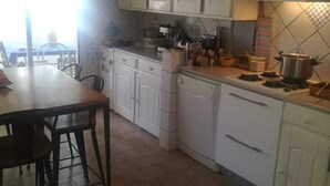 Una cocina con armarios blancos, una mesa de comedor con sillas y un ventanal que proporciona luz natural.